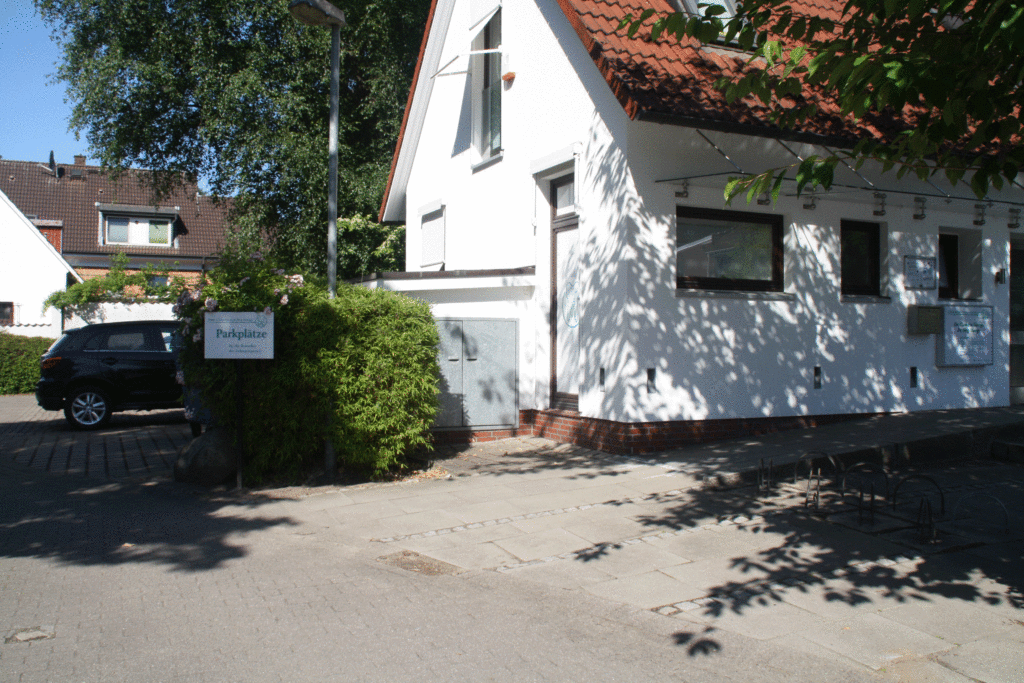 Zu sehen ist der äußere Eingangsbereich der Praxis und ein Teil des Parkplatzes.